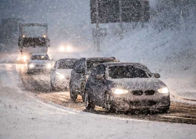 samochody jadące zaśnieżoną ulicą padający śnieg