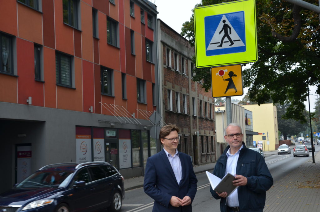 Krzysztof Łoziński oraz Stanisłąw Torbus przy przjeściu dla piezych za njimi znaki drogowe uwaga przejście