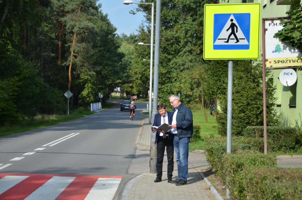 dwóch mężczyzn przegląda dokumnetację, stoją obok przejscia dla pieszych