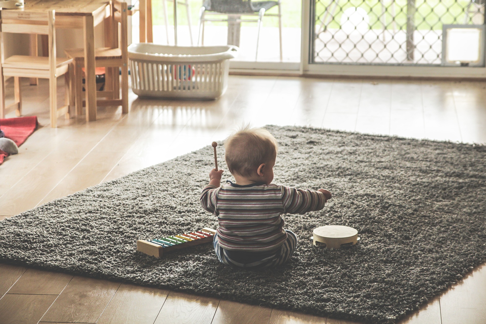 małe dziecko siedzi na dywanie bawi się cymbałkami