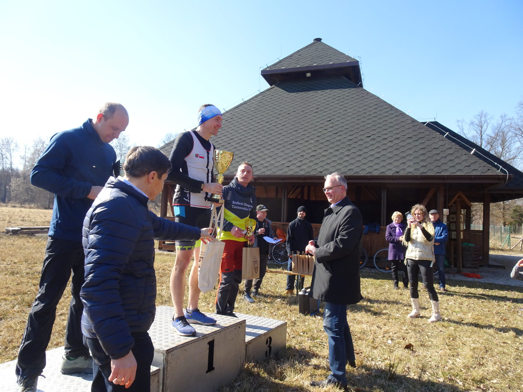 wręczenie nagród, kilka osób stoi na podium i kilka obok