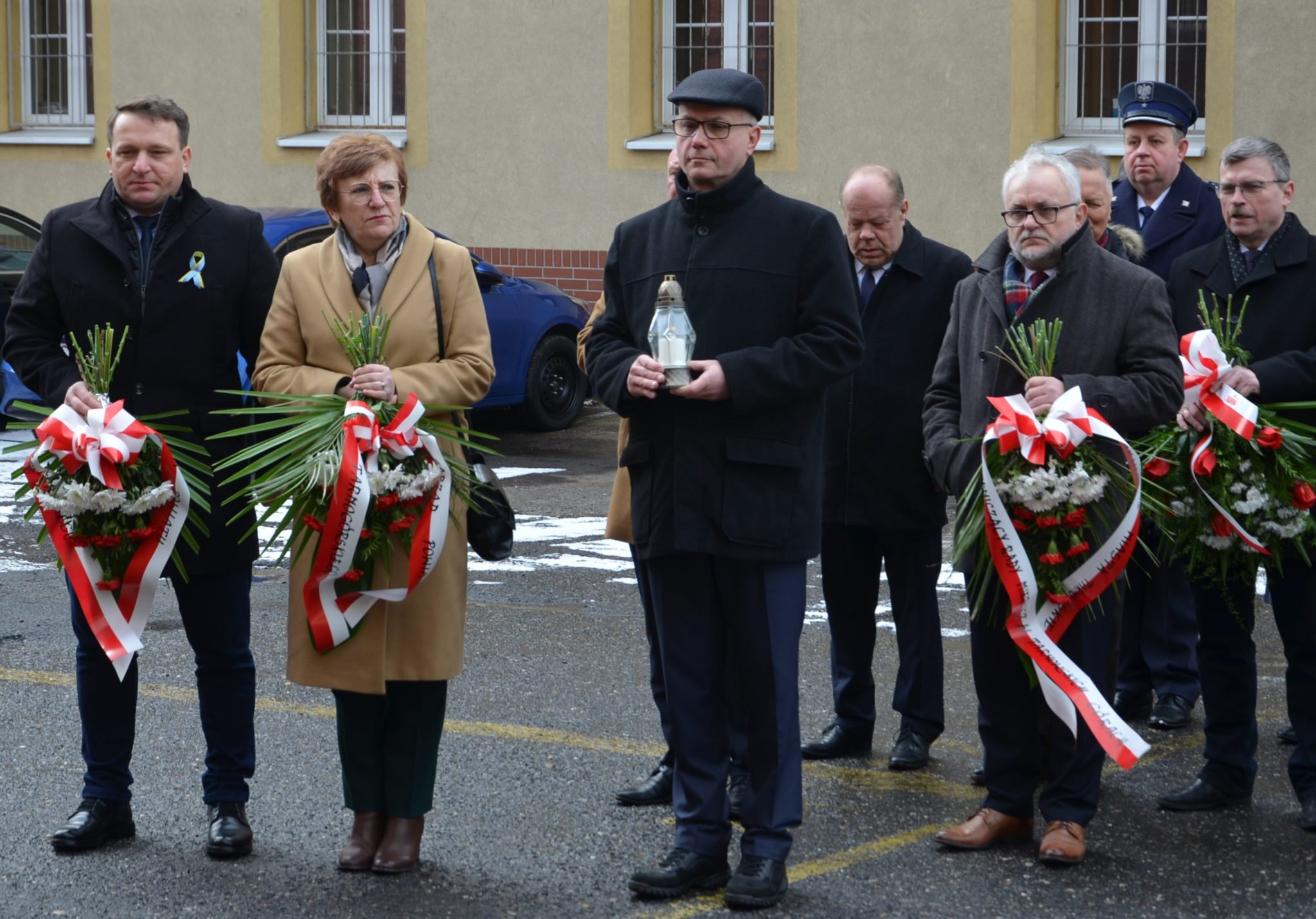 przedstawiciele powiatu skladaj kwiaty pod tablica przy areszczie ślwdczym w Tarnowskich Górach 