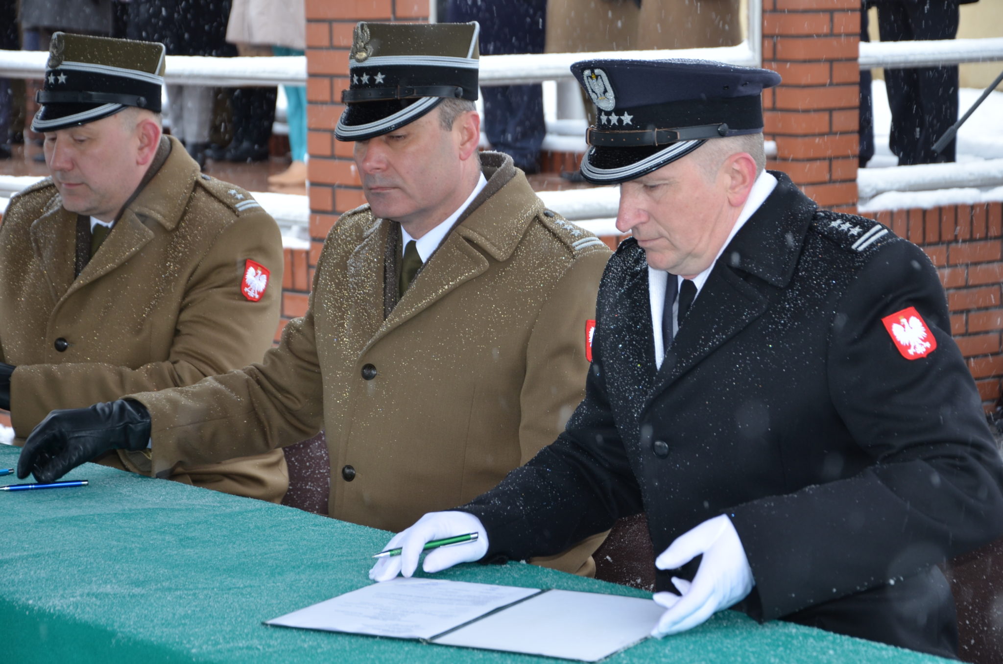 trzech męzczyzn w mundurach galowych podczas podpisania aktu mianowania