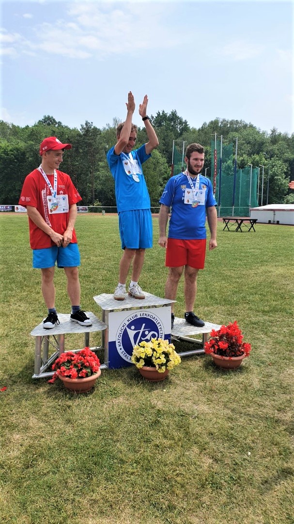 mężczyźni stojący na podium z medalami na szyi