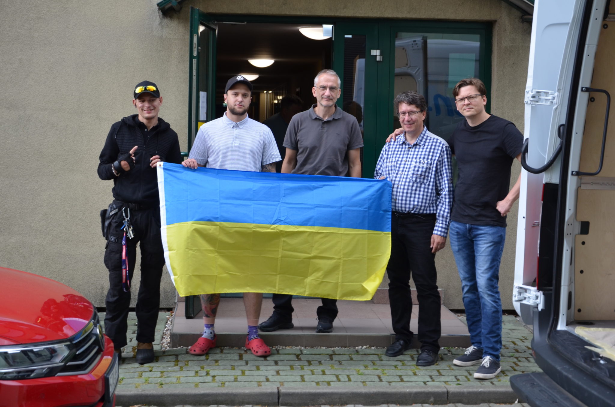 kilku mężczyzn stoi przed budynkiem starostwa z flagą Ukrainy 