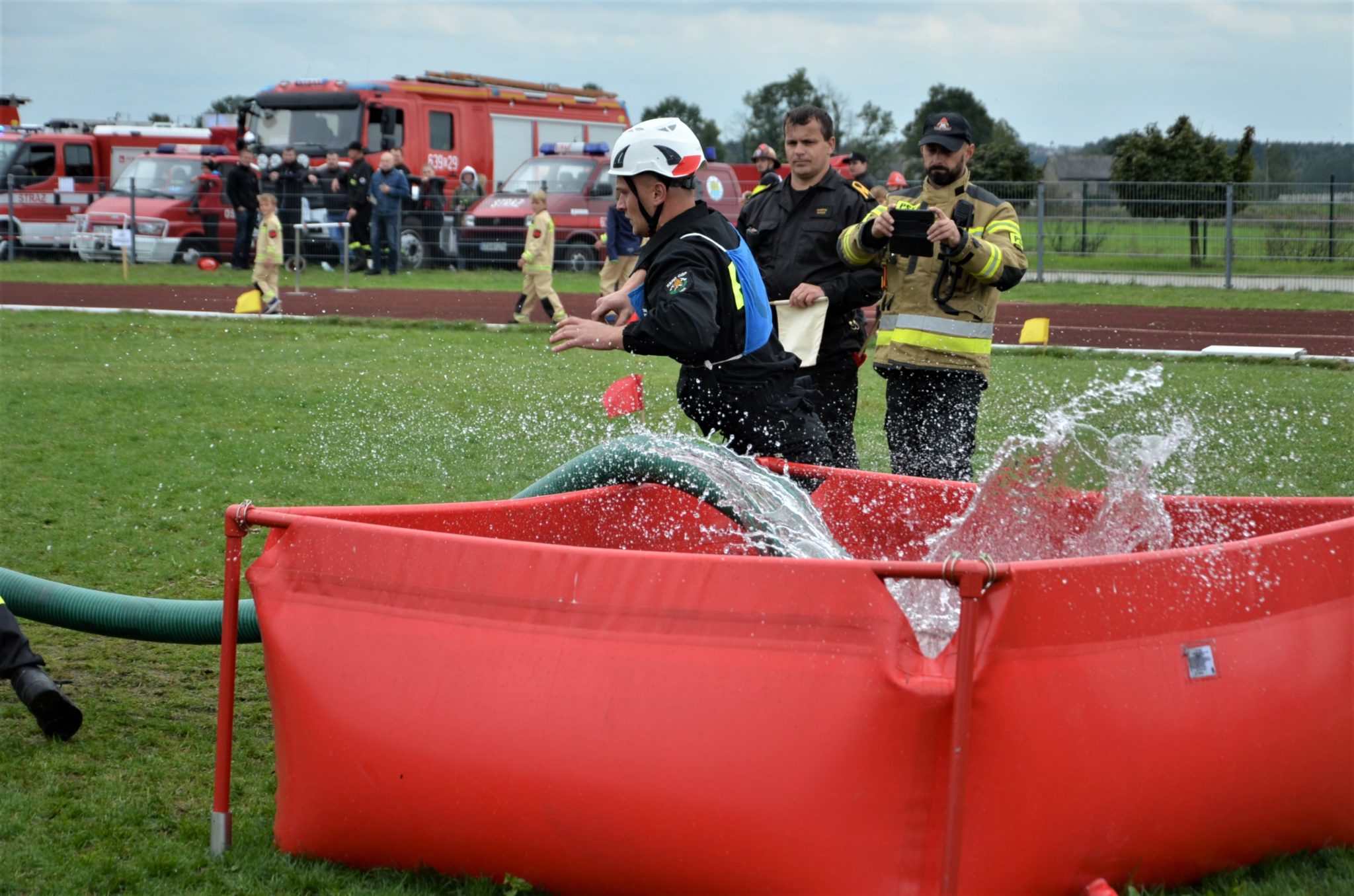 strażacy wrzucają węża strażackiego do basenu