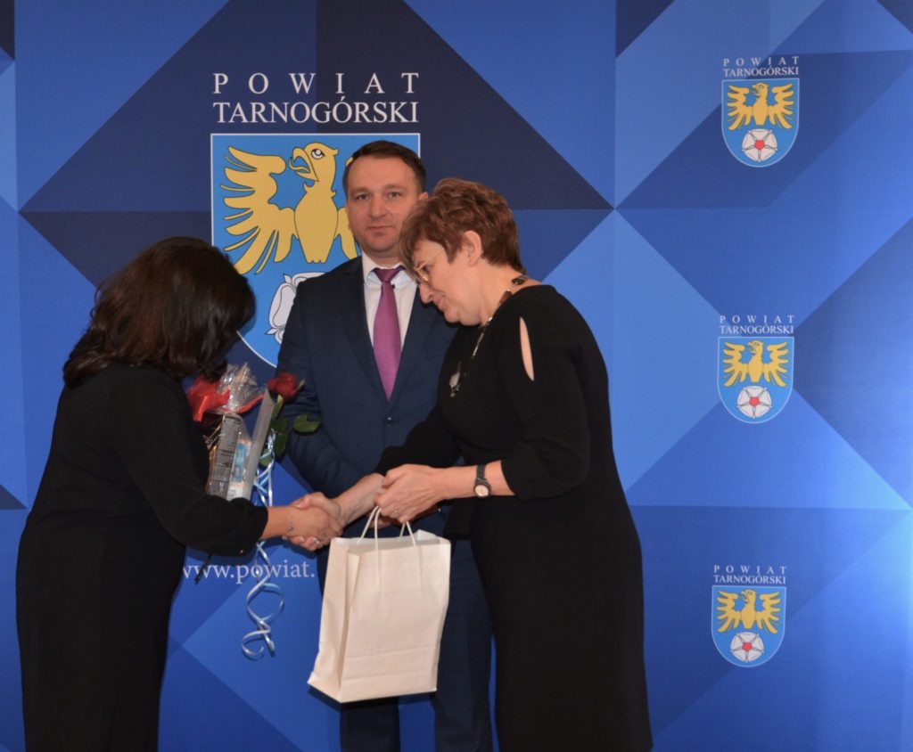 Starosta i przewodniczący Rady Powiatu składająca gratulacje nauczycielce.