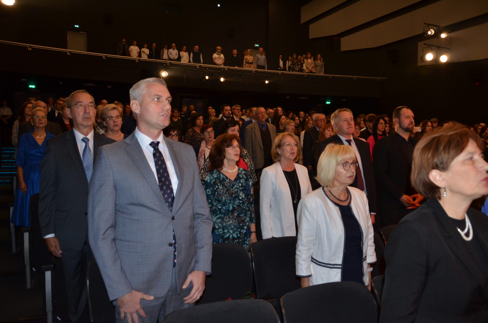 Duża grupa osób, które stoją blisko siebie w dużym pomieszczeniu.