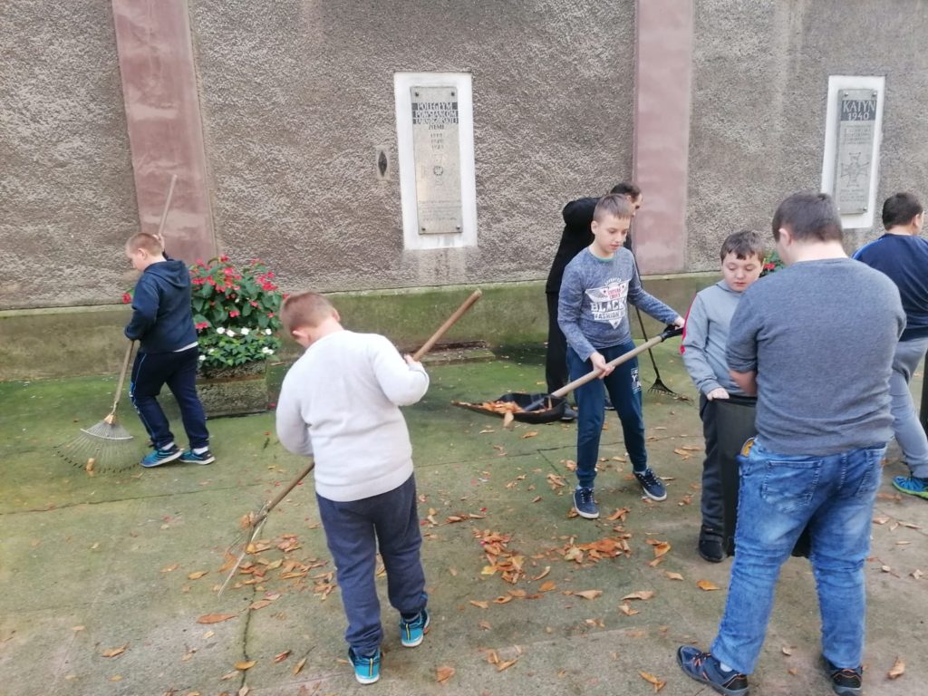 grupa młodych osób podczas sprzątania przed kościołem