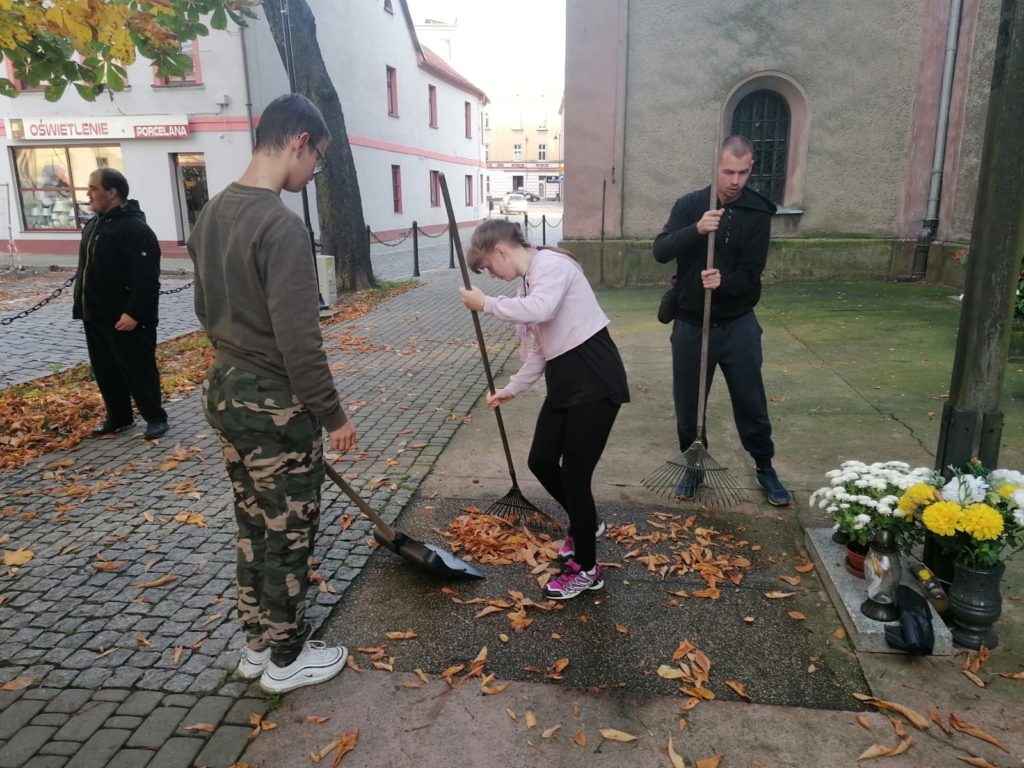 grupa młodych osób podczas sprzątania przed kościołem