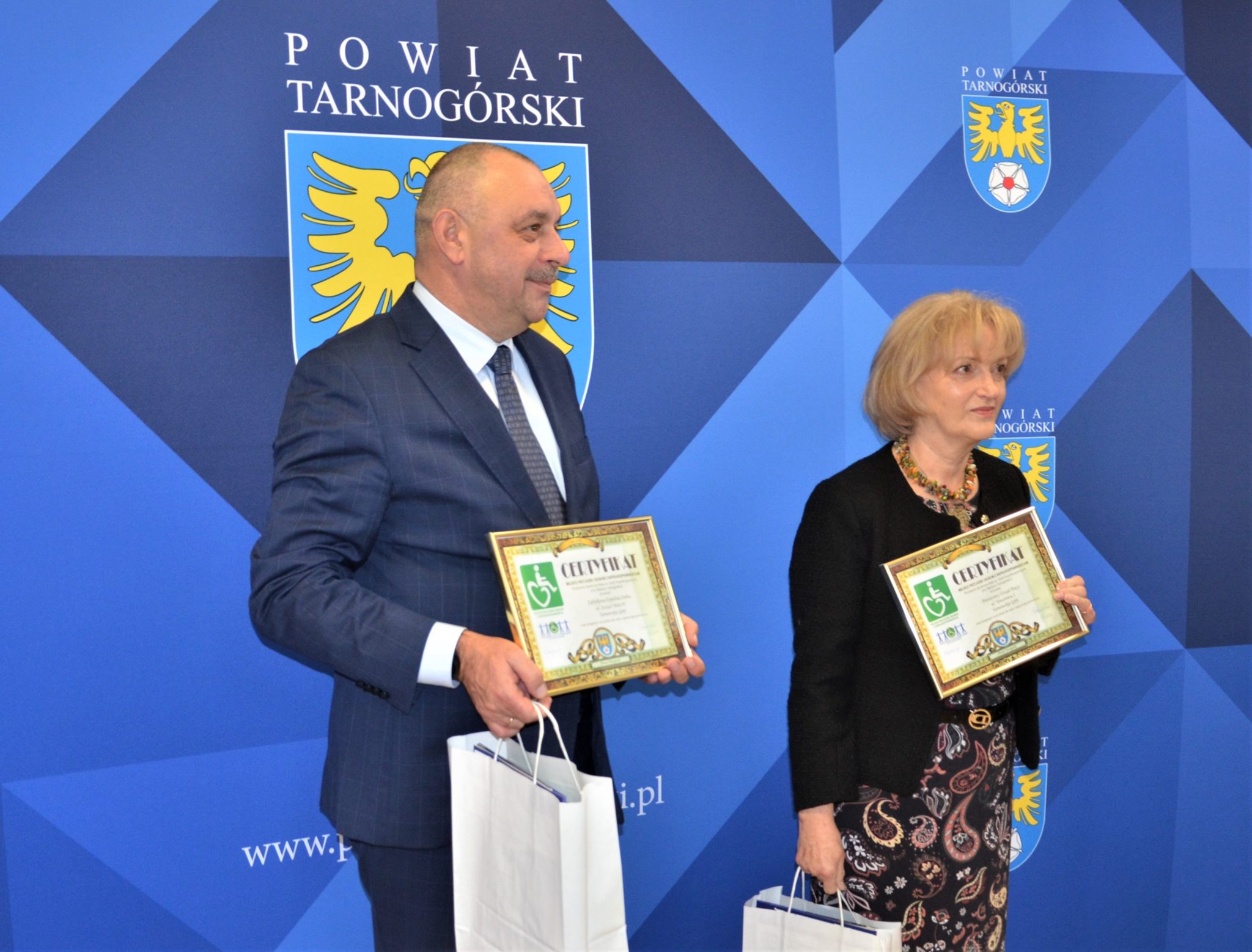 Kobieta i mężczyzna trzymający w rękach certyfikaty.