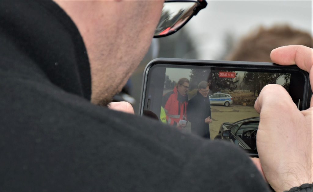 Osoba trzymająca w ręku telefon i nagrywająca film.