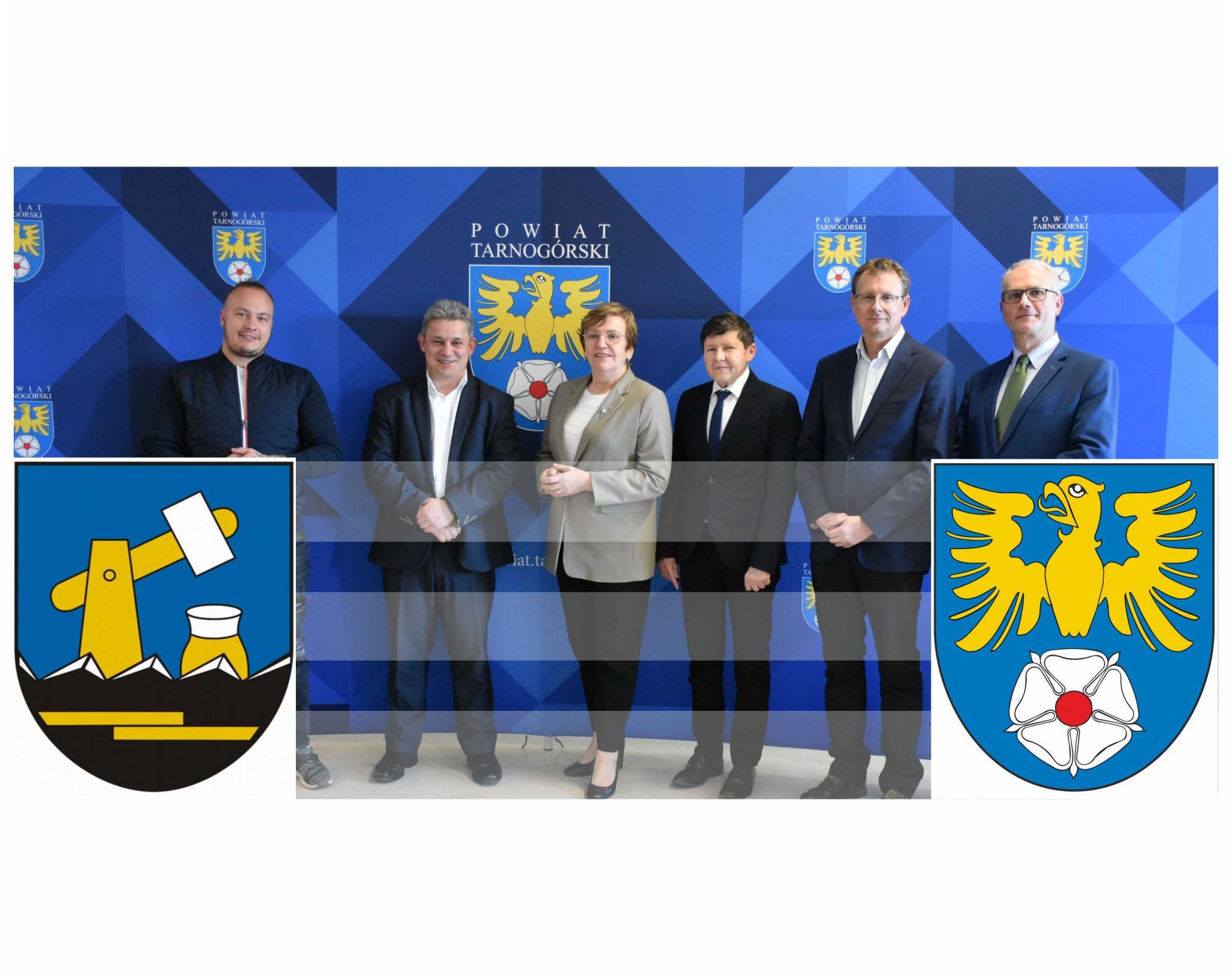 Kilka osób stojących obok siebie, w tle baner z logo powiatu tarnogórskiego. Po prawej stronie logo powiatu tarnogórskiego, a po lewej stronie logo miasta kalety.