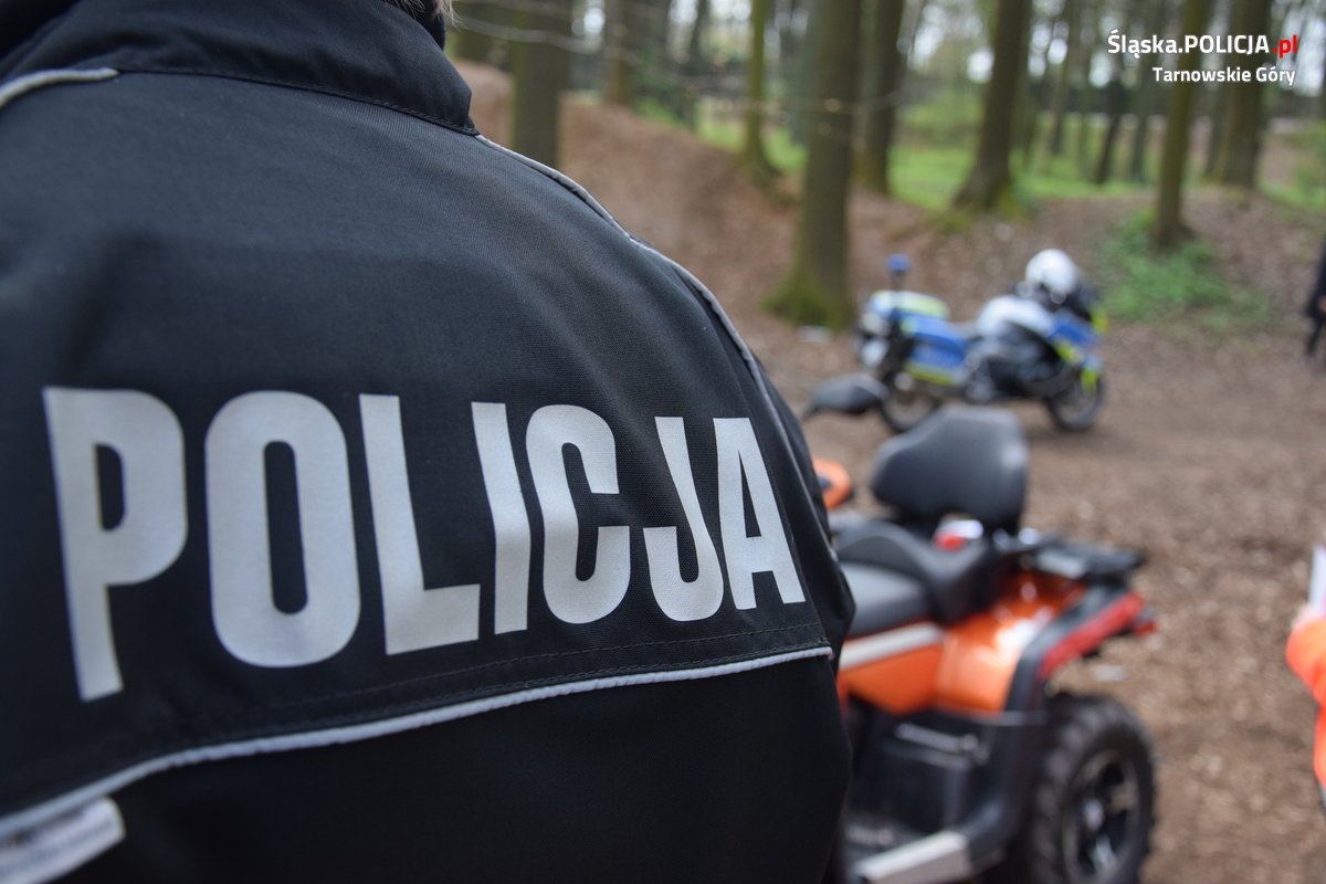 Napis Policja na mundurze, w tle motocykl.