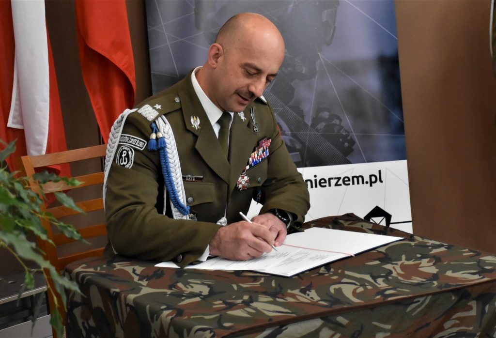 Mężczyzna w mundurze podczas podpisywania dokumentu.