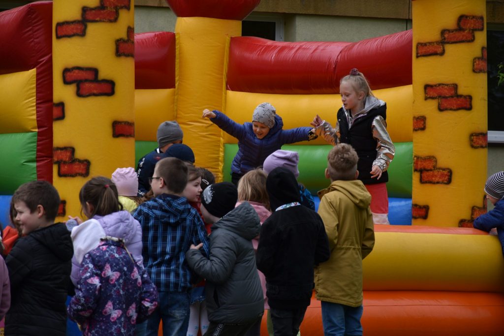 Grupa dzieci podczas zabawy na dmuchanym zamku.