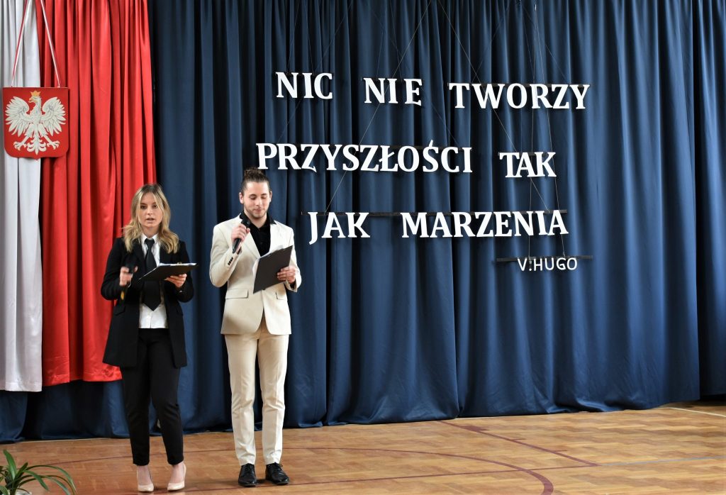 Dziewczyna i chłopak, którzy trzymają mikrofony i prowadzą akademię.