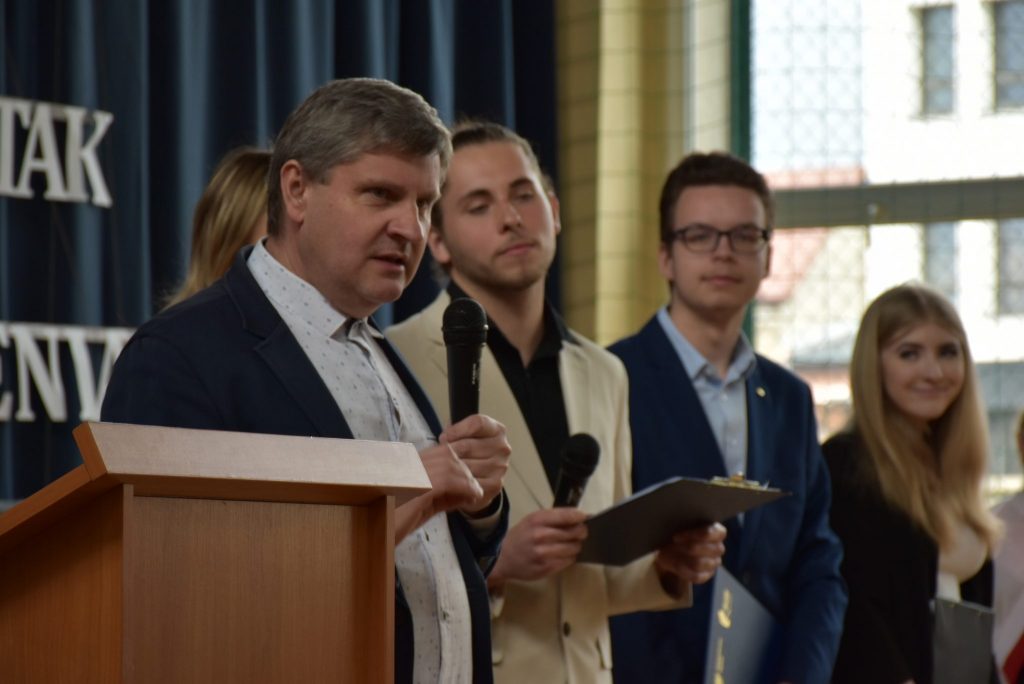 Dyrektor ZSGH podczas przemowy na akademii. W tle grupa młodzieży.