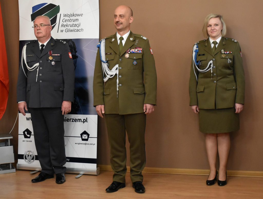 Trzy osoby w mundurach stoją obok siebie. W tle baner z napisem Wojskowe Centrum Rekrutacji w Gliwicach.
