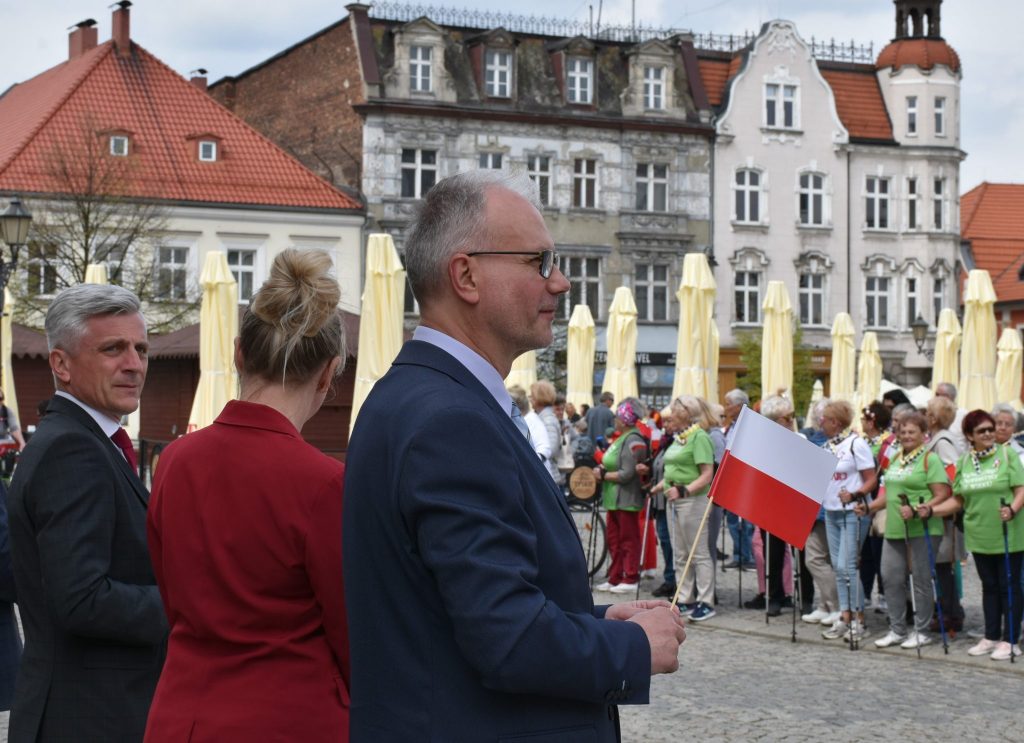 Grupa osób na tarnogórskim rynku, w tle zabudowa miejska.