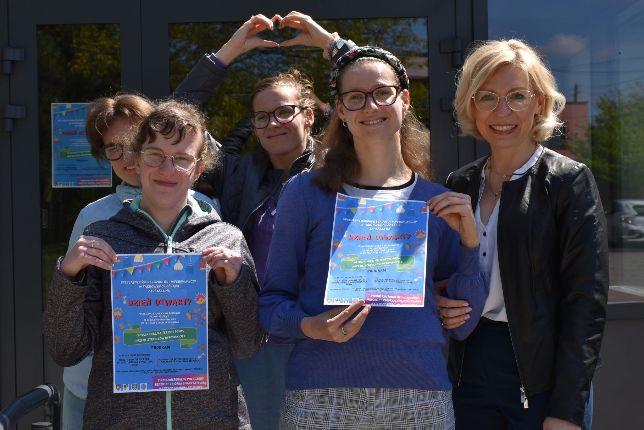 Grupa młodzieży z Panią Dyrektor z Specjalnego Ośrodka Szkolno Wychowawczego w Tarnowskich Górach. Dwie dziewczyny trzymają w rękach plakaty z zaproszeniem na dzień otwarty w dniu 18 maja.