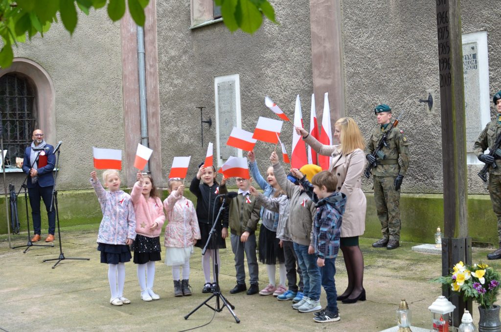 grupa dzieci podczas wystepu macha flagami Polski