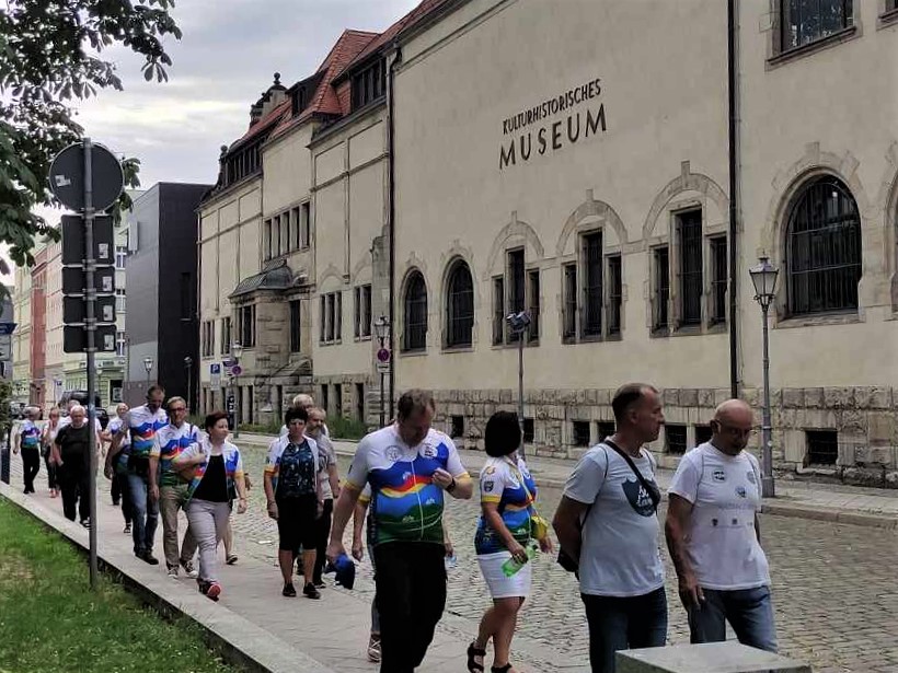 Grupa osób, które idą chodnikiem przy dużym budynku Muzeum.