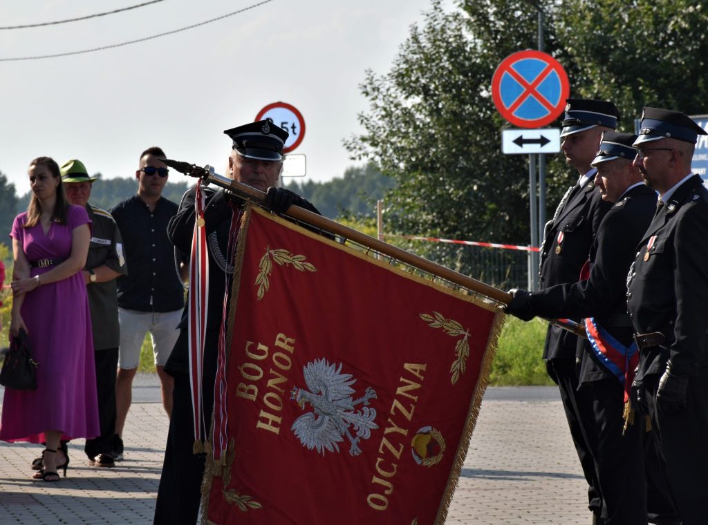 Sztandar oraz grupa osób w mundurach.