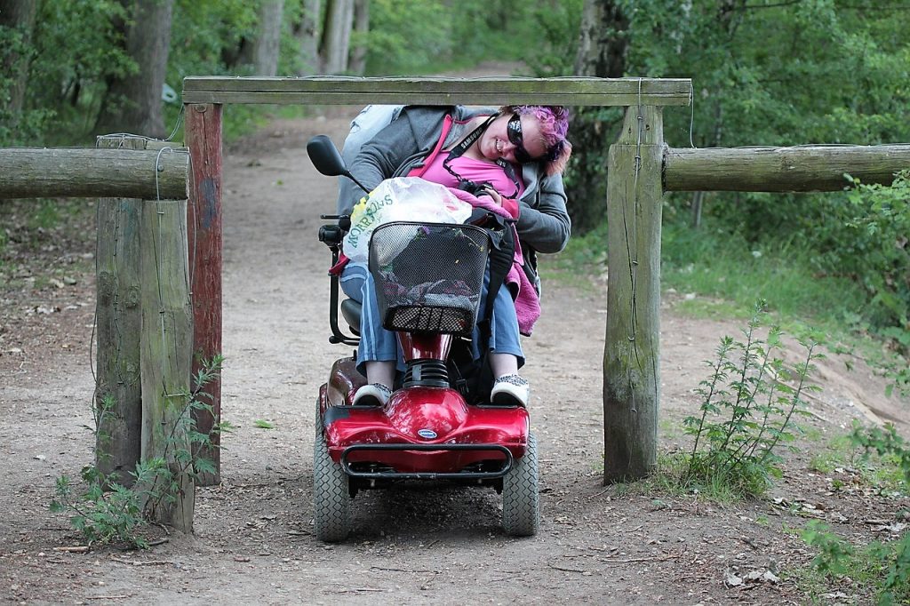 kobieta na wózku przejeżdża pod barierą drewnianą