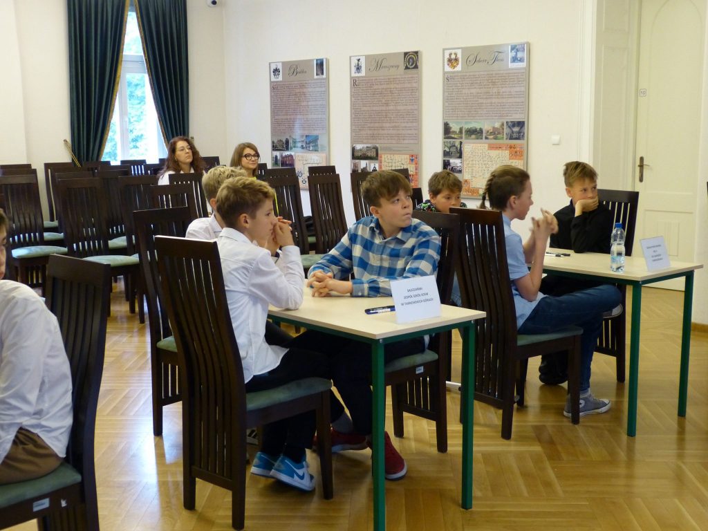 dzieci i młodzież siedzą przy stolikach w sali