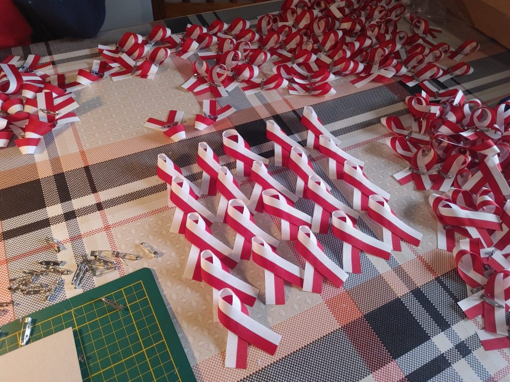 Biało- czerwone wstążki ułożone na blacie stołu.