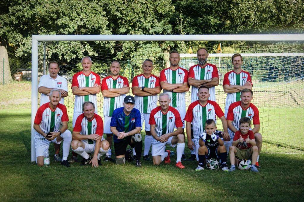 grupa piłkarzy ustawieni do zdjęcia, za nimi bramka piłkarska