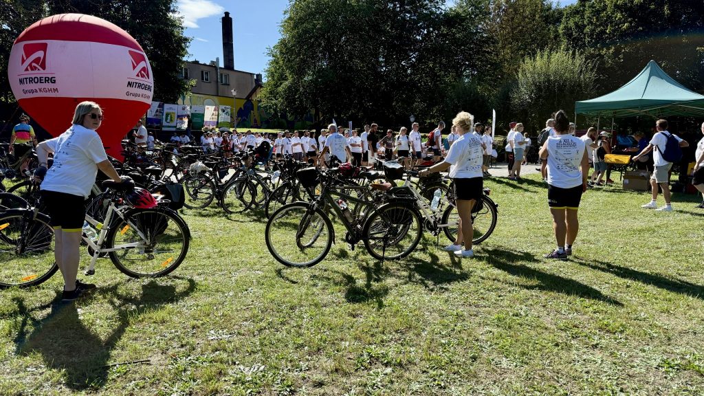 zawodnicy, ubrani w stroje sportowe, przed nimi duża ilość rowerów, wszystkie stoją na trawie