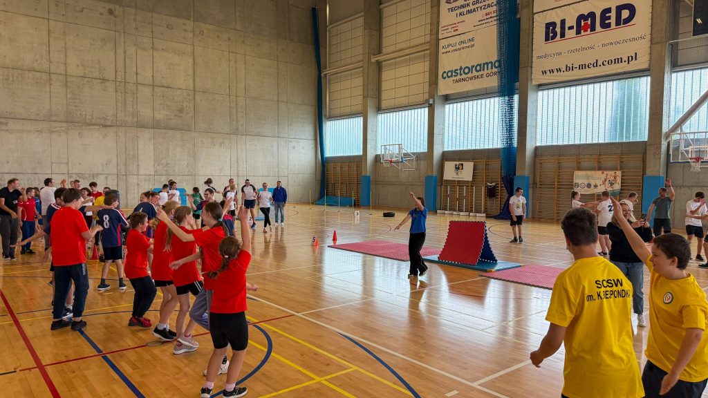 hala sportowa, boisko, podzielone drużyny w strojach sportowych, w tle banery reklamowe 