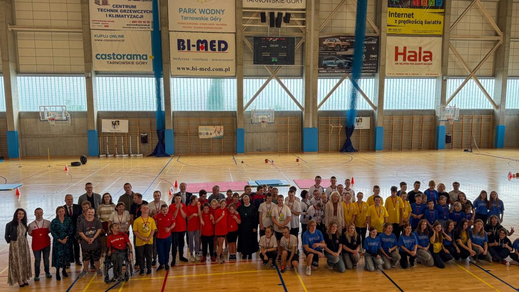 gruba zawodników w strojach sportowych na hali sportowej, w tle kolorowe banery i tablice
