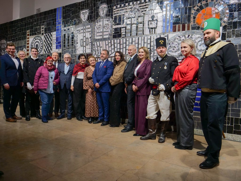 grupa osób, pozuje do zdjęcia, za nimi mural